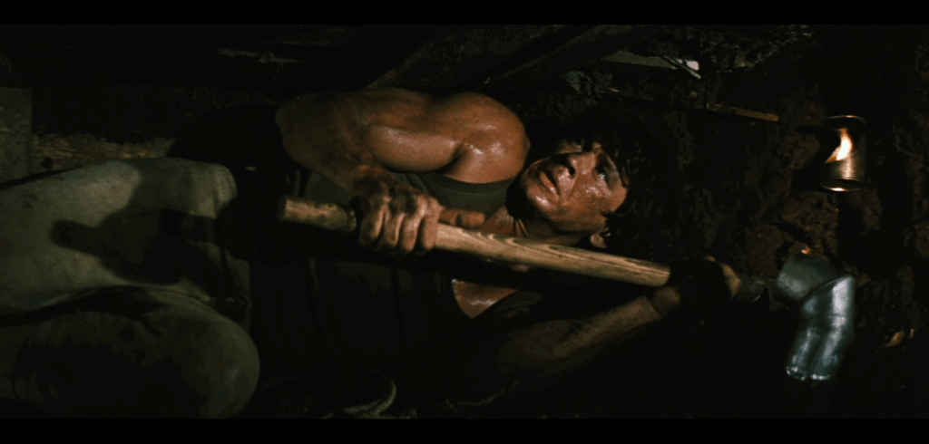 Charles Bronson in The Great Escape; he's lying in a tunnel as he digs it, looking worried