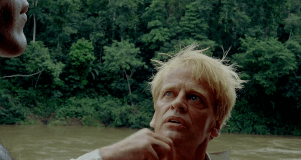 Klaus Kinski in Fitzcarraldo, mad determination in his eyes as he looks up towards Cholo who is barely in frame on the left